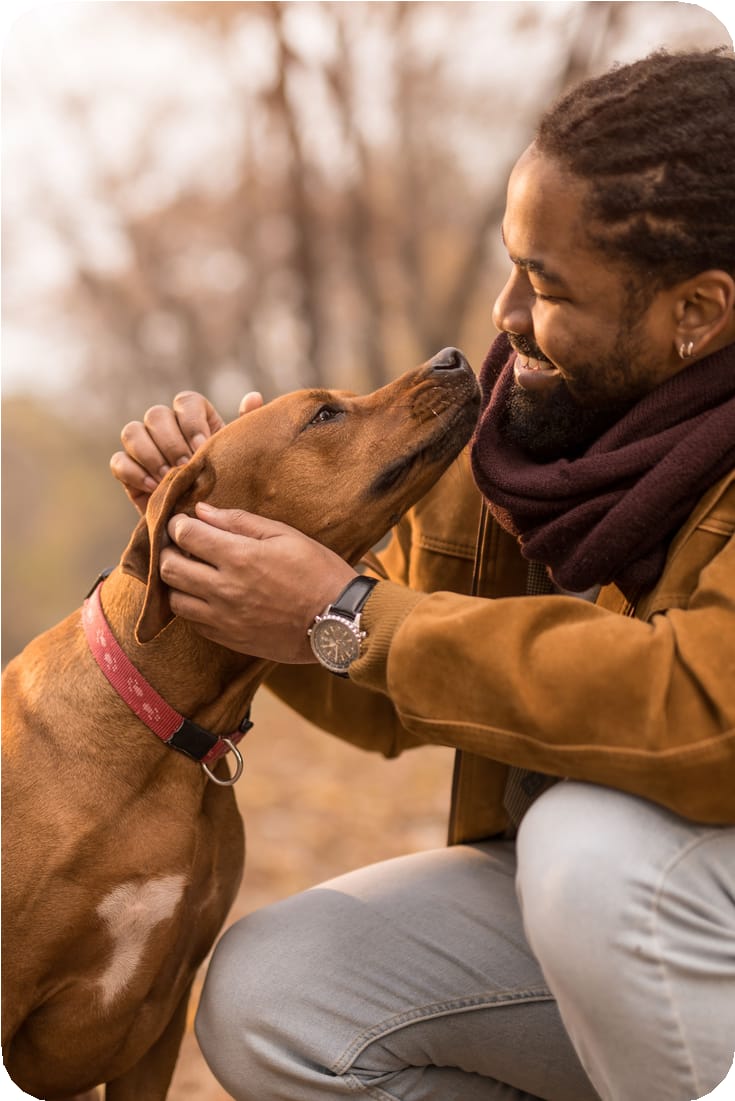 Un homme caresse son chien en souriant